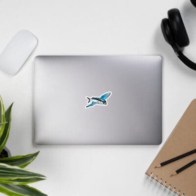 BoldWater flying fish sticker in blue, displayed on laptop with office supplies